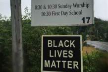 A sign for Putney Friends Meeting with a Black Lives Matter sign hanging below it