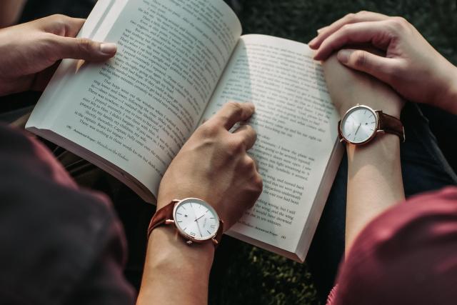 The image is of an open book held by two pairs of hands