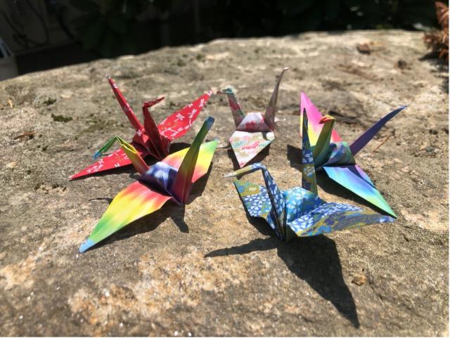 A photo of colorful origami cranes set on a rock