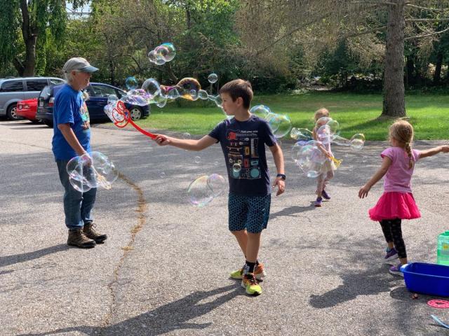 An adult and three children playing with bubble wands
