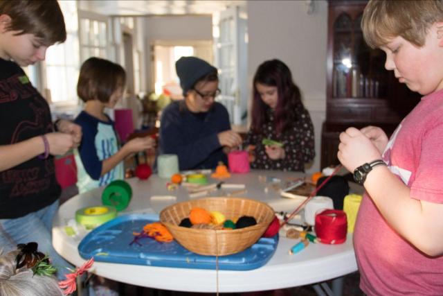 children gathered around a table, working with string and yarn