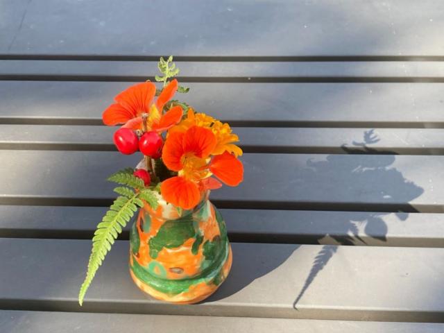 A photo of an orange-and-green vase of nasturtiums