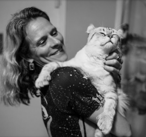 A black-and-whie image of a smiling woman holding a cat
