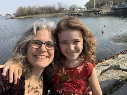 Photo of a smiling woman and young girl with a background of water