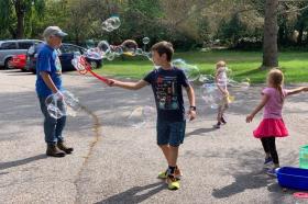 An adult and three children playing with bubble wands