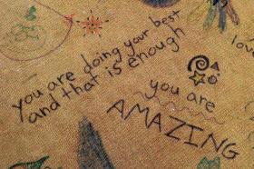 Photo shows drawings and messages on old carpet and one message reads you are doing your best and that is enough