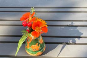 A photo of an orange-and-green vase of nasturtiums